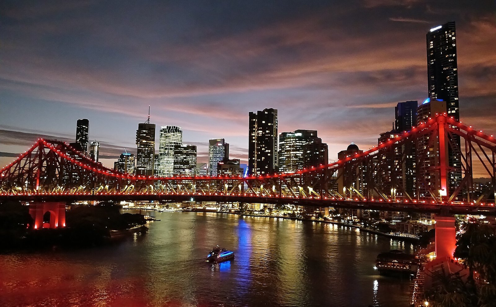 The Story Bridge lit red at dusk with the Brisbane skyline
